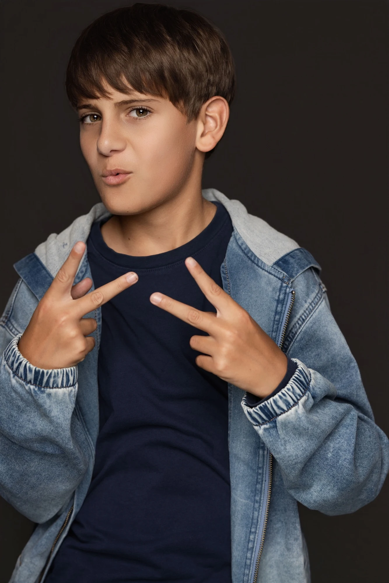 Brandon wearing a denim jacket and holding up peace signs